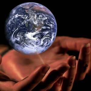 Hand floating on black background holding glass model of a globe